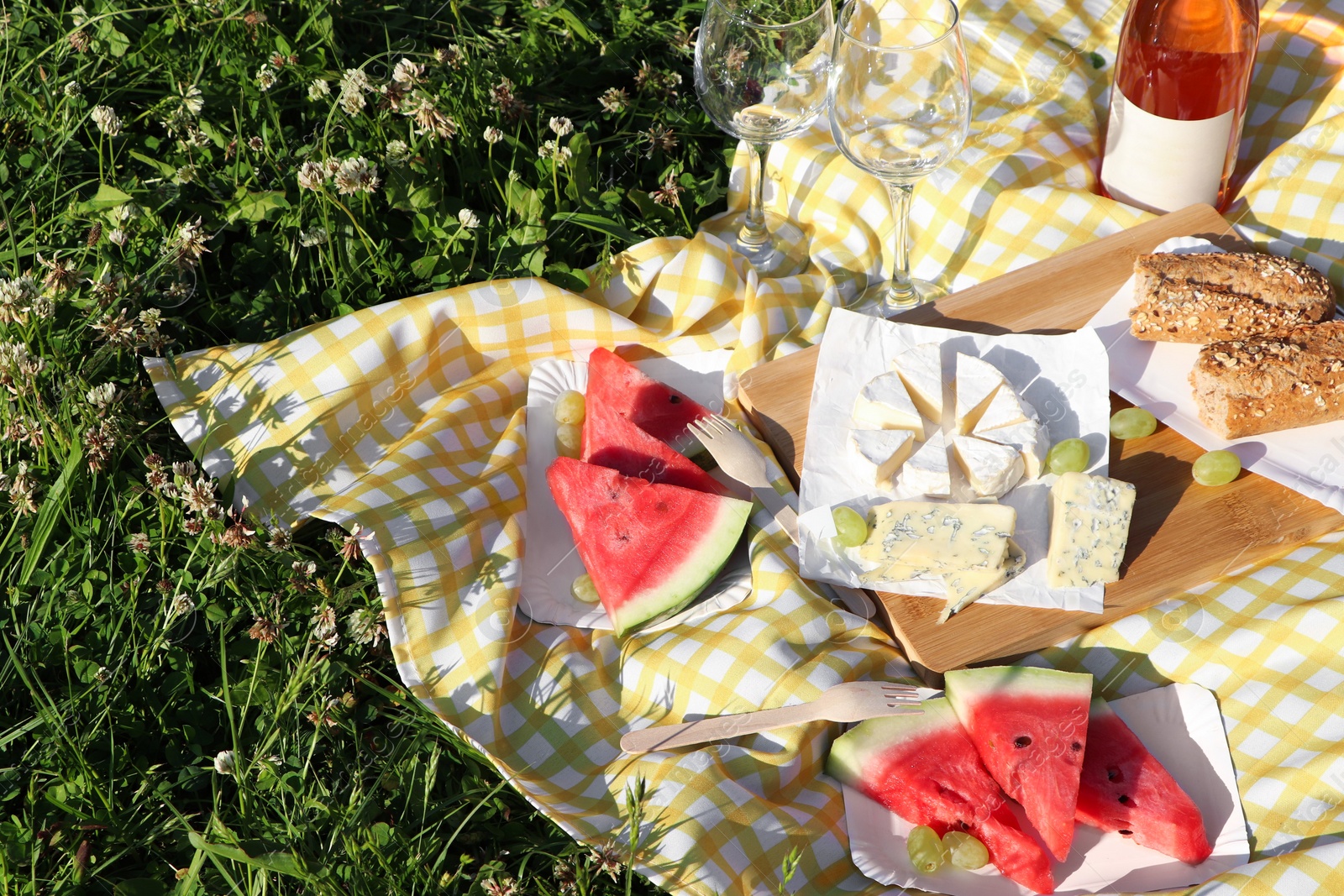 Photo of Picnic blanket with delicious food and wine on green grass outdoors