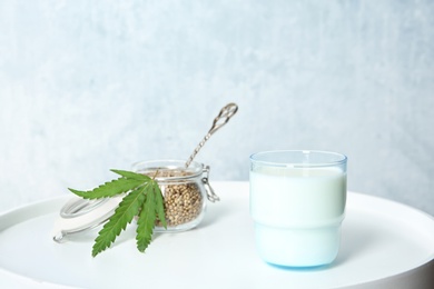 Photo of Glass of hemp milk and jar with seeds on white table