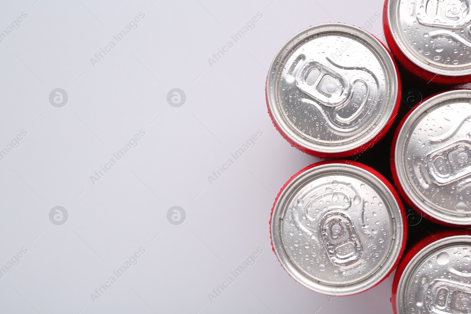 Photo of Energy drinks in wet cans on light grey background, top view. Space for text