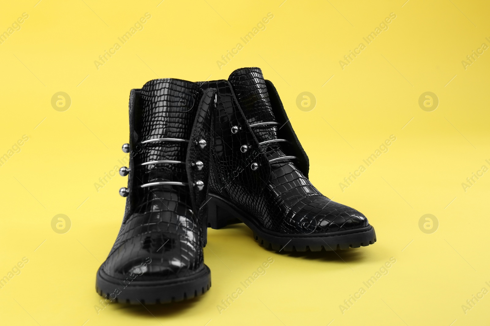 Photo of Pair of stylish ankle boots on yellow background