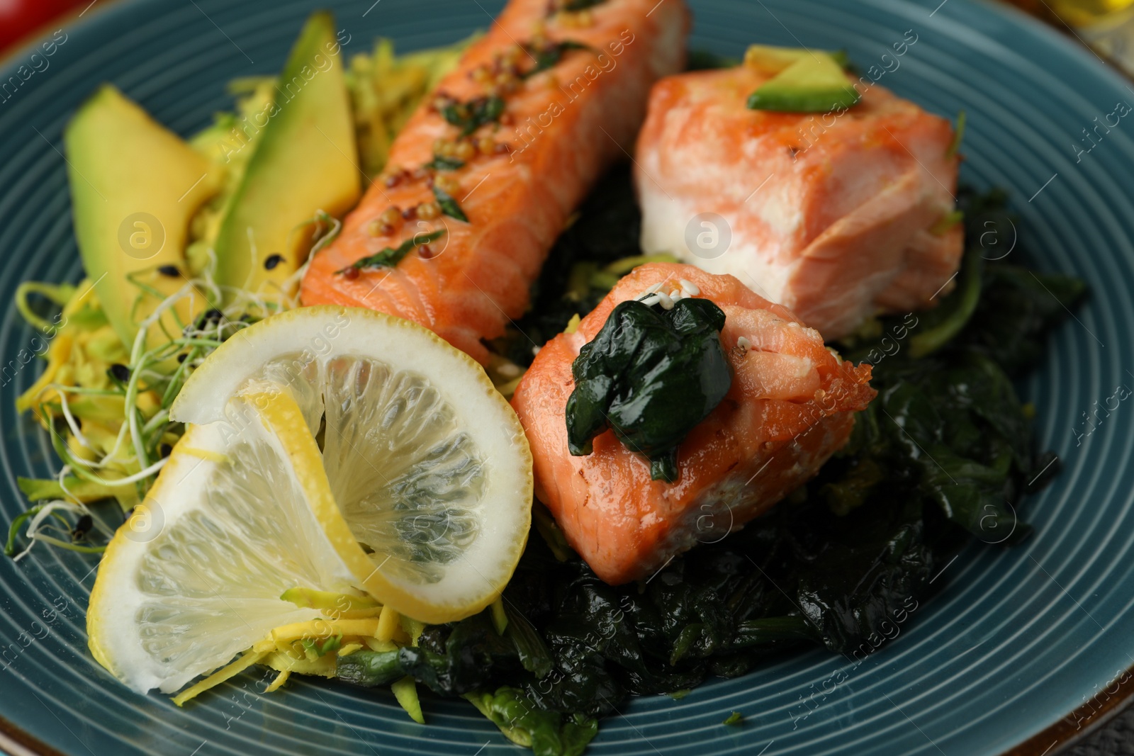 Photo of Tasty freshly cooked salmon with spinach on plate, closeup