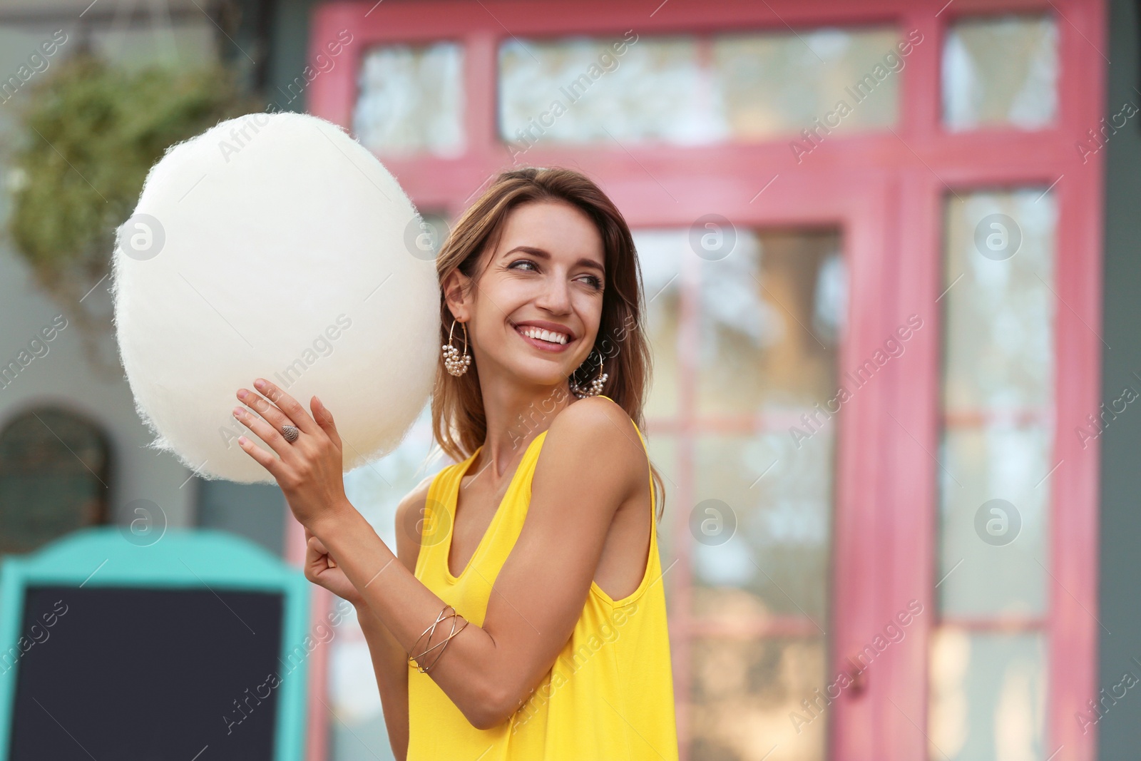 Photo of Happy young woman with cotton candy outdoors