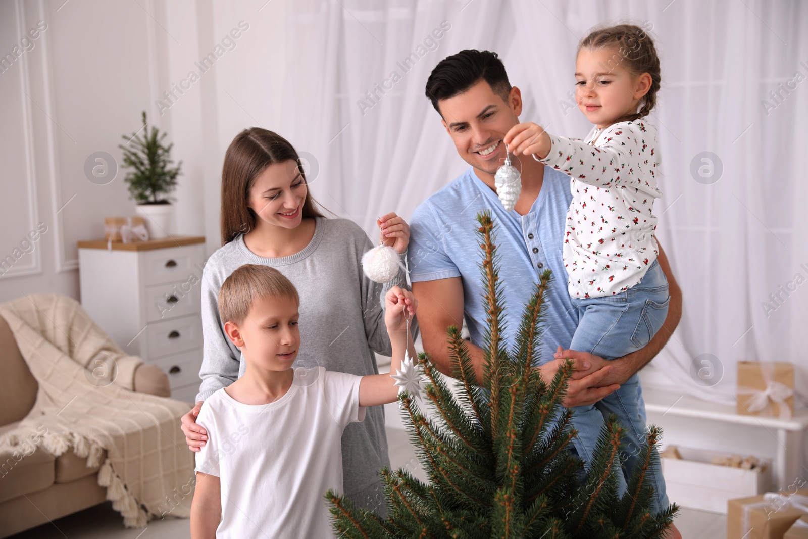 Photo of Happy family with cute children decorating Christmas tree together at home