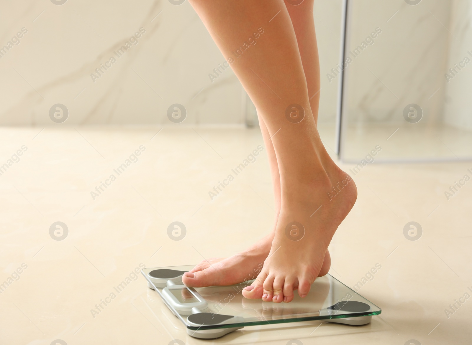 Photo of Woman standing on scales in bathroom. Overweight problem