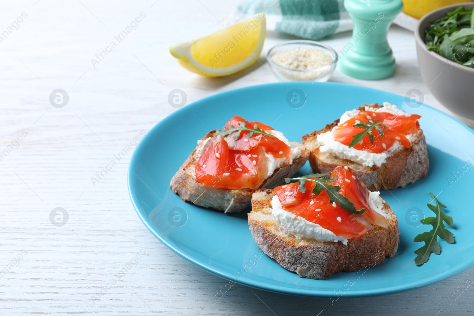 Photo of Delicious sandwiches with cream cheese, salmon and arugula on white wooden table