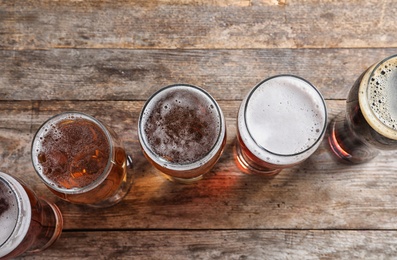 Photo of Glasses with different types of cold tasty beer on wooden background