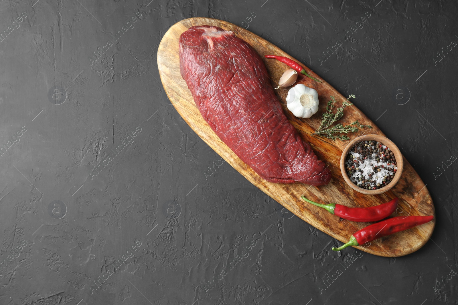 Photo of Piece of raw beef meat, products and spices on dark textured table, top view. Space for text