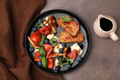Delicious salad with brie cheese, berries and balsamic vinegar on brown table, flat lay