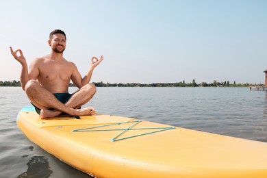 Man practicing yoga on SUP board on river