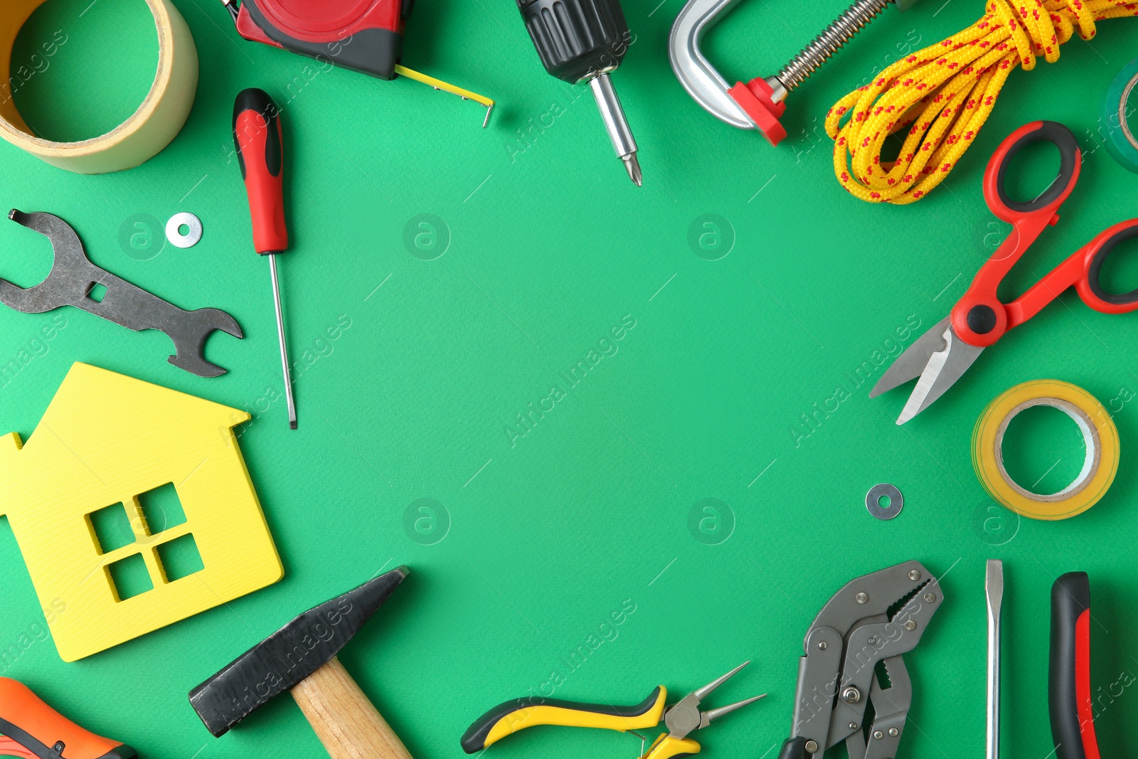 Photo of Frame of repair tools and house figure on green background, flat lay. Space for text