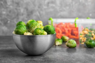 Photo of Bowl with frozen Brussel sprouts on table. Vegetable preservation