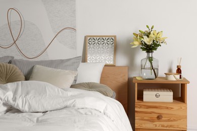 Photo of Vase with bouquet of fresh flowers on wooden nightstand in bedroom