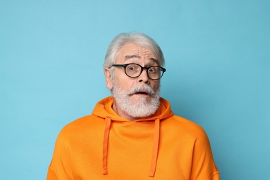 Senior man with mustache on light blue background