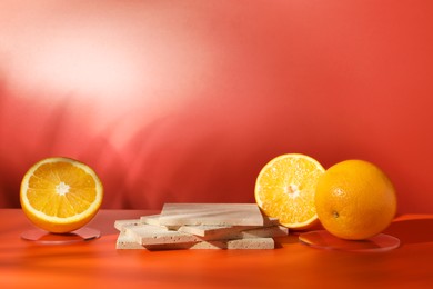 Photo of Presentation for product. Podium and tasty fresh oranges on red background, space for text