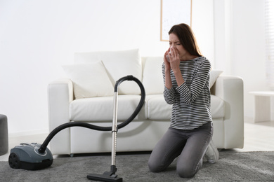 Photo of Young woman suffering from dust allergy while vacuuming house