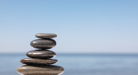 Photo of Stack of stones against blurred seascape, space for text. Zen concept