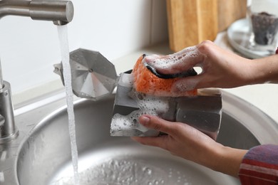 Photo of Woman washing moka pot (coffee maker) above sink in kitchen, closeup