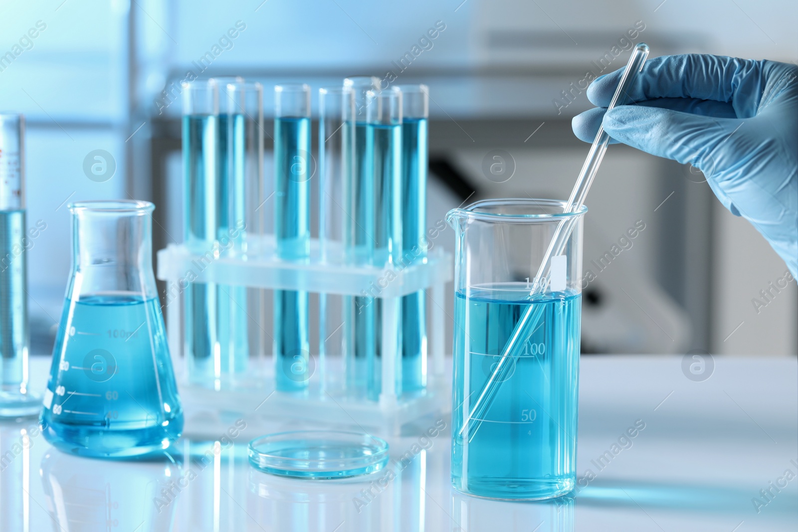 Photo of Scientist taking sample of light blue liquid in laboratory, closeup