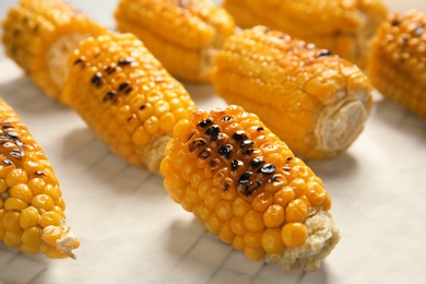 Fresh grilled tasty corn cobs on parchment paper, closeup