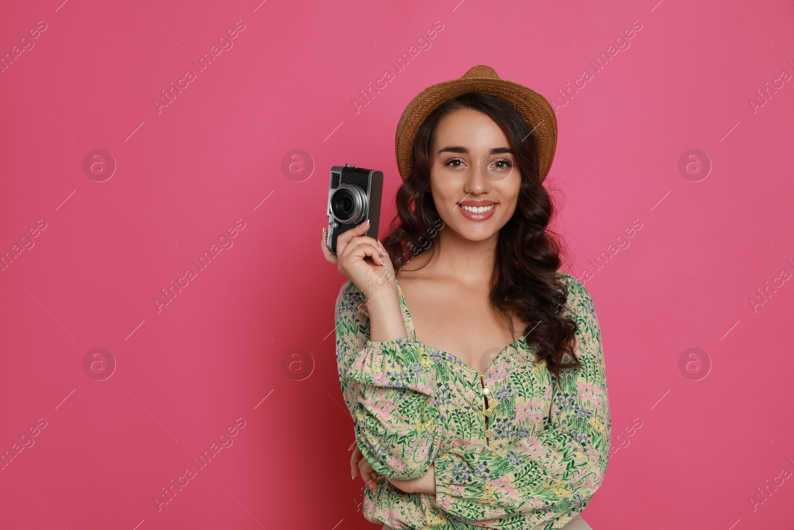 Photo of Beautiful young woman with straw hat and camera on pink background. Space for text
