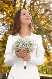 Photo of Happy young bride with beautiful bouquet outdoors. Wedding day