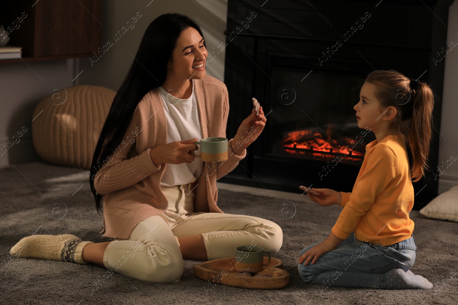 Photo of Happy mother and daughter spending time together on floor near fireplace at home