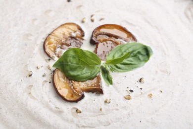 Photo of Tasty homemade mushroom soup with fresh basil leaves as background, closeup