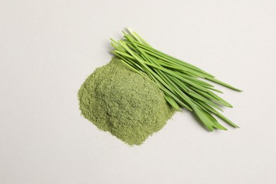 Photo of Pile of wheat grass powder and fresh green sprouts on light table, flat lay