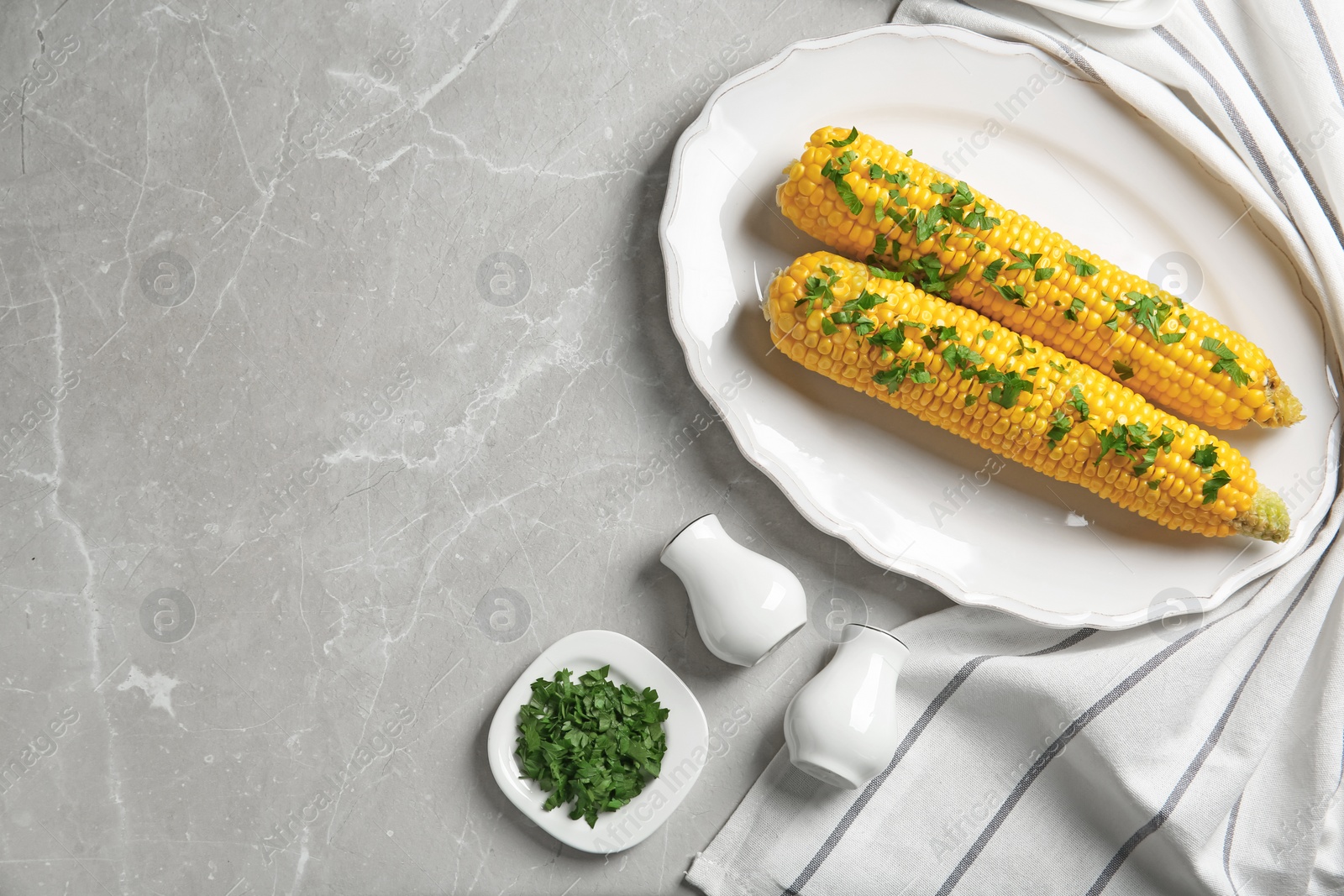 Photo of Plate with delicious boiled corn cobs and parsley on light table, top view. Space for text