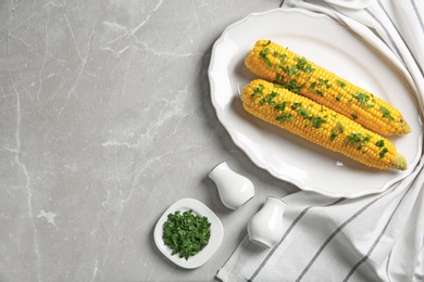 Photo of Plate with delicious boiled corn cobs and parsley on light table, top view. Space for text