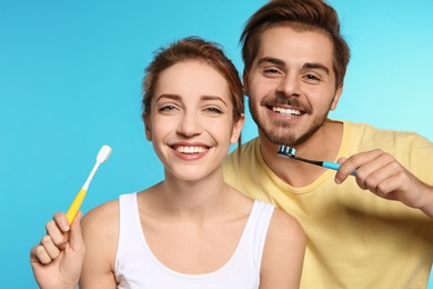 Portrait of young couple with toothbrushes on color background