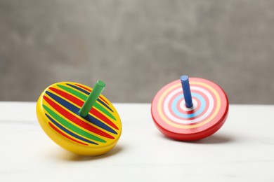 Two bright spinning tops on white table, closeup