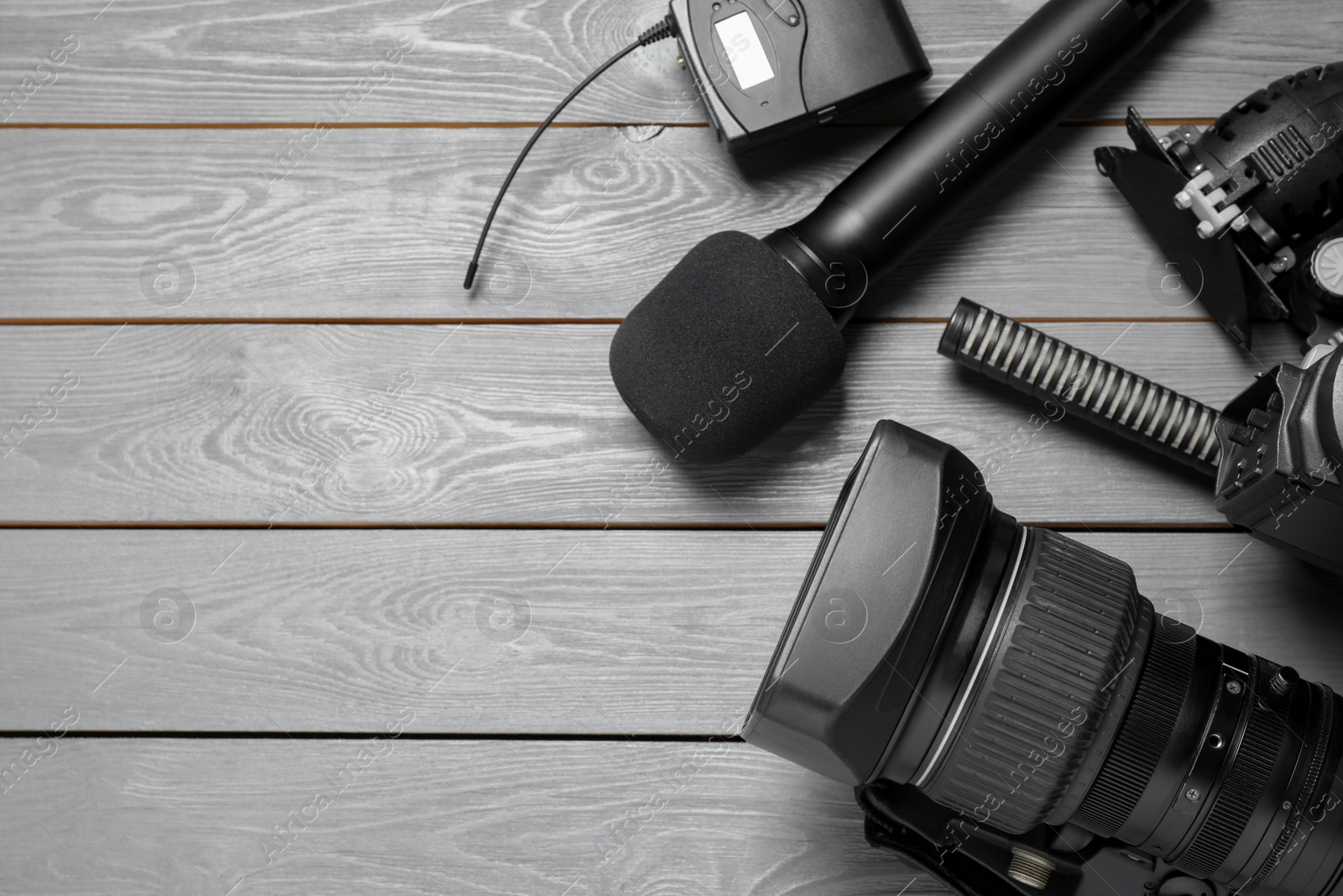 Photo of Flat lay composition with camera and video production equipment on grey wooden background. Space for text