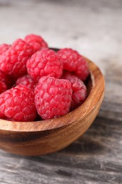 Photo of Tasty ripe raspberries in bowl on wooden table, closeup