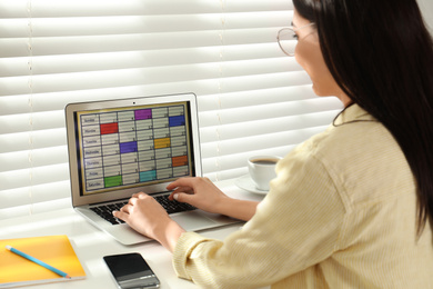 Photo of Young woman using calendar app on laptop in office