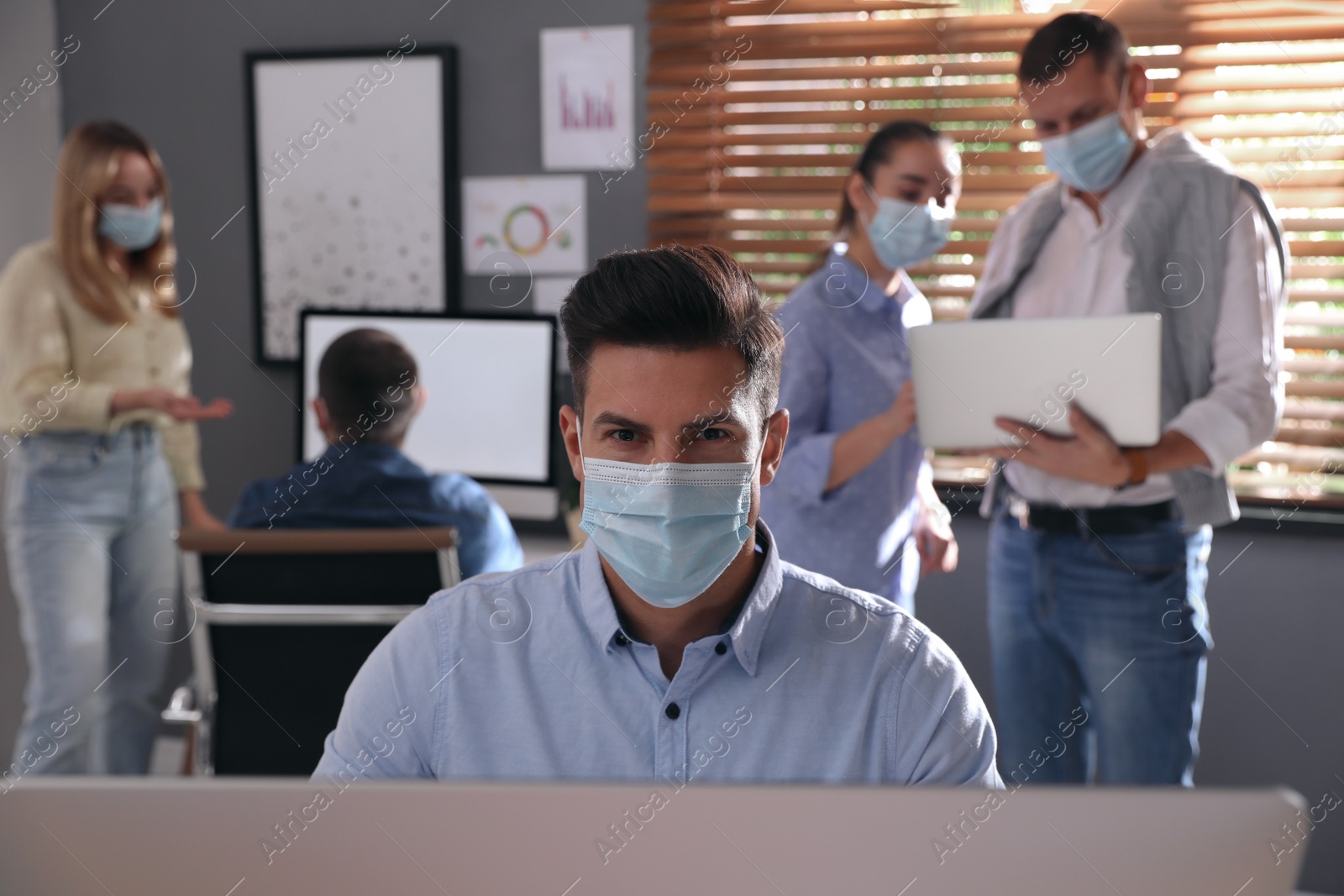 Photo of Worker with mask in office. Protective measure during COVID-19 pandemic