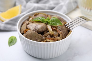 Photo of Delicious fried chicken liver with onion and basil in bowl on white table, closeup