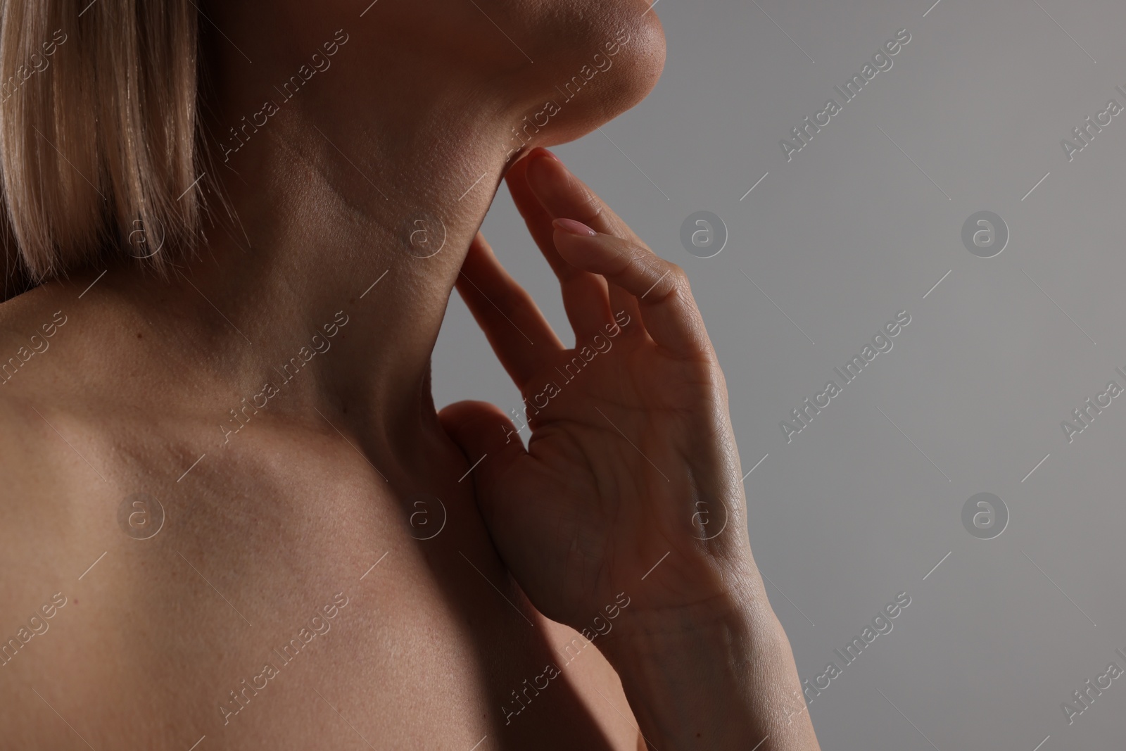 Photo of Woman touching her neck on grey background, closeup