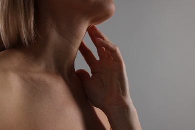 Photo of Woman touching her neck on grey background, closeup