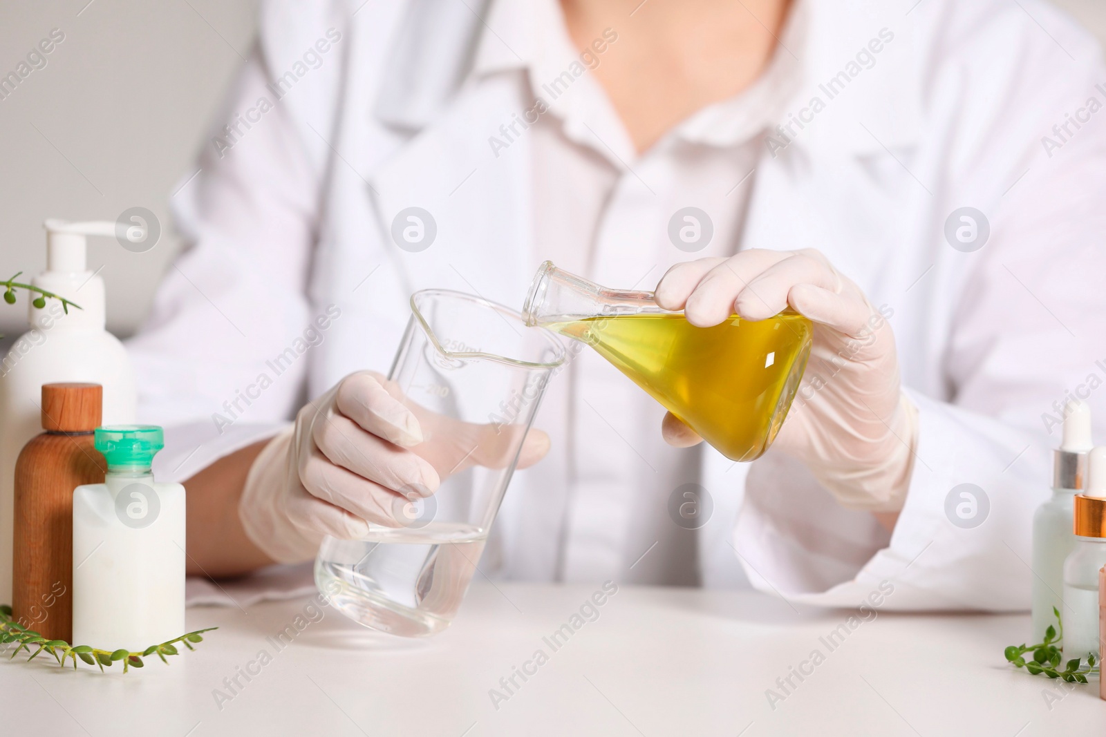 Photo of Dermatologist developing cosmetic product at white table indoors, selective focus