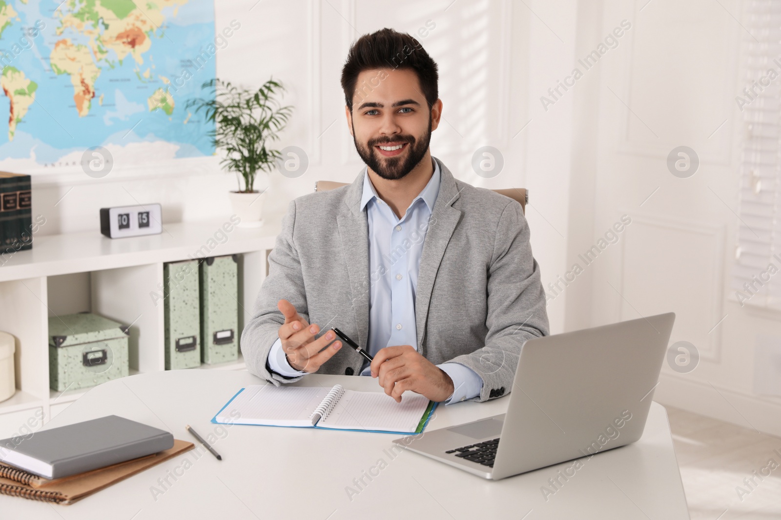 Photo of Happy manager with notebook sitting at desk in travel agency