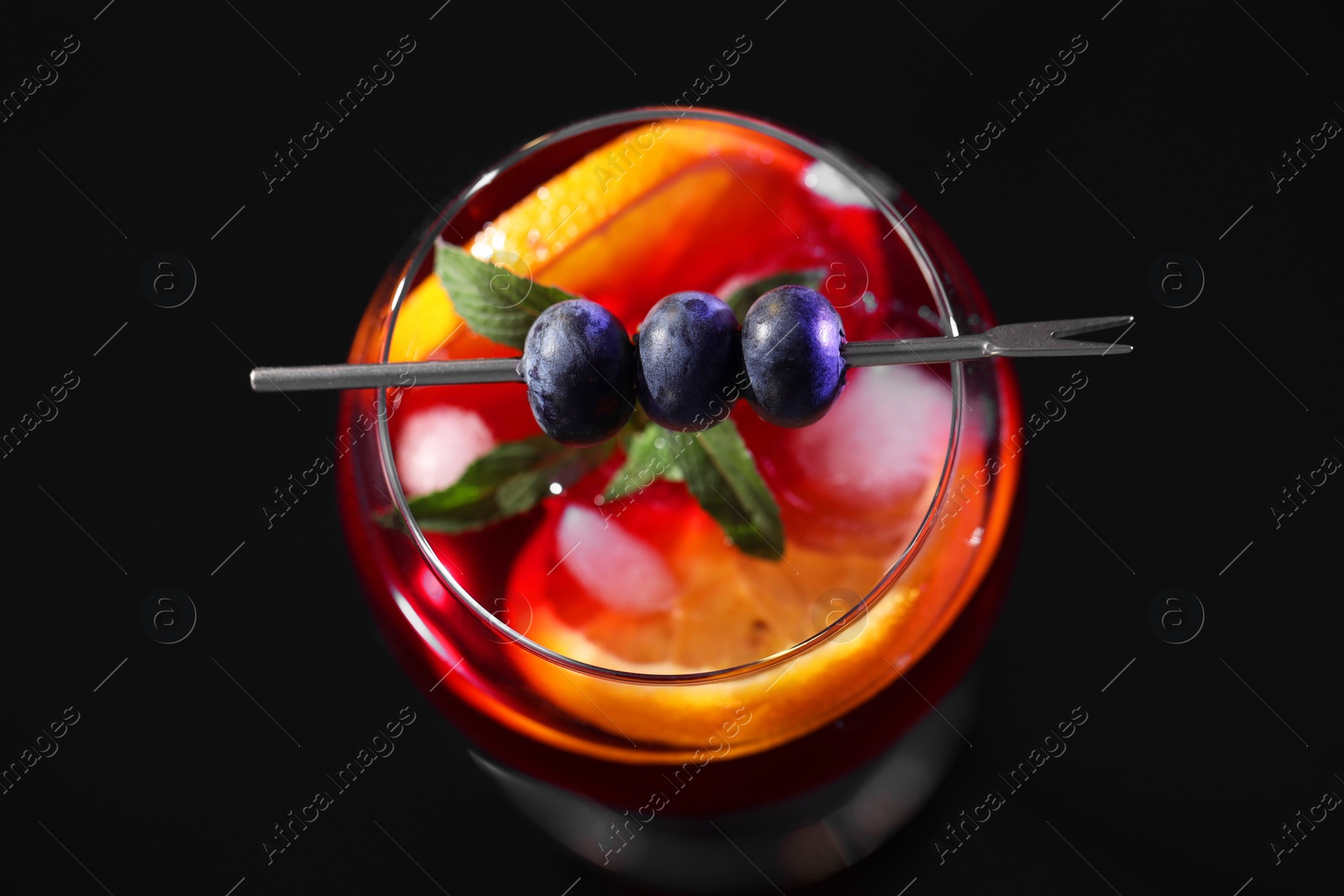 Photo of Glass of delicious refreshing sangria on black table, above view