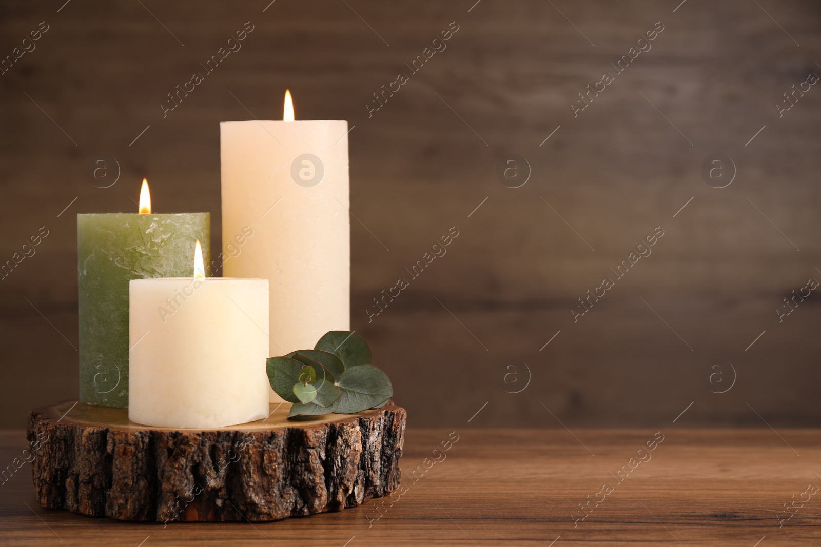 Photo of Beautiful candles and eucalyptus branch on wooden table, space for text