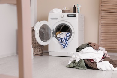 Photo of Laundry room interior with pile of dirty clothes and washing machine near wall