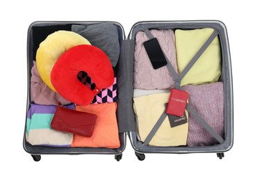 Photo of Soft travel pillows, smartphone, passports and other items in open suitcase isolated on white, top view