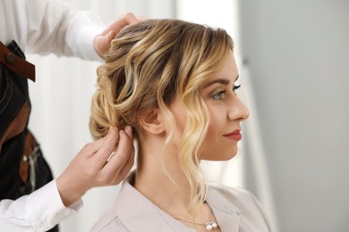 Photo of Hair styling. Professional hairdresser working with client indoors, closeup