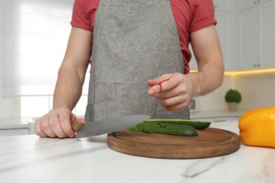 Photo of Man cut finger with knife while cooking at white marble table in kitchen, closeup