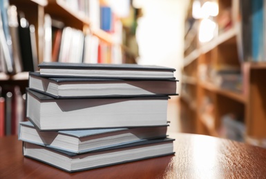 Photo of Stack of books on table in library. Space for text