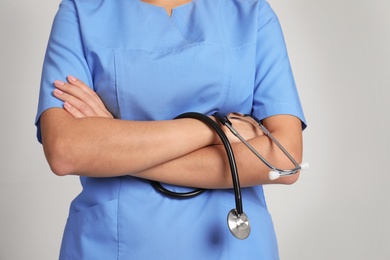 Photo of Medical assistant with stethoscope on color background, closeup