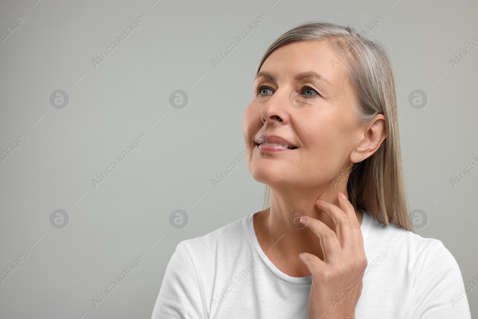 Photo of Beautiful woman touching her neck on grey background, space for text
